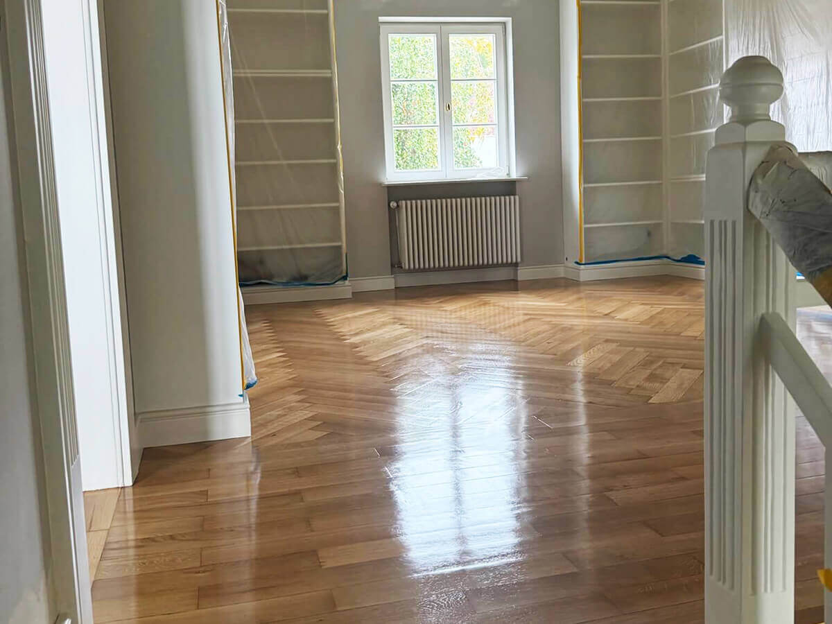 Versiegeltes Fischgrätparkett im Flur einer Altbauwohnung mit Treppengeländer